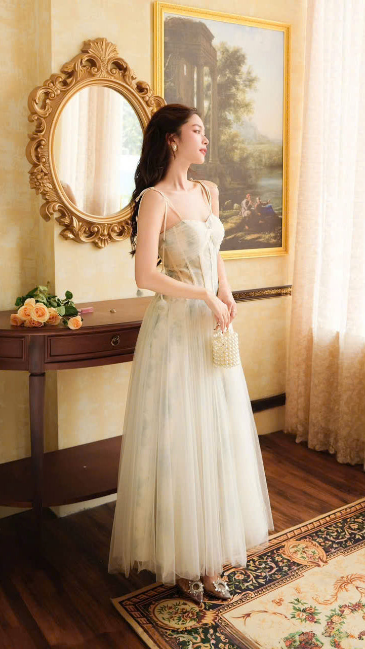 Elegant woman in a vintage-inspired tulle gown, The VEROA Elysian Dream Dress, featuring a corset bodice, delicate spaghetti straps, and a flowing A-line skirt in a soft watercolor print. She stands gracefully in a classic, opulent room with antique decor, exuding timeless sophistication and fairy-tale charm