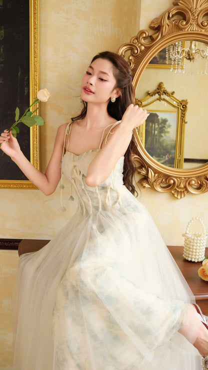 Elegant woman in a vintage-inspired tulle gown, The VEROA Elysian Dream Dress, featuring a corset bodice, delicate spaghetti straps, and a flowing A-line skirt in a soft watercolor print. She stands gracefully in a classic, opulent room with antique decor, exuding timeless sophistication and fairy-tale charm